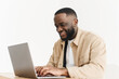 © etonastenka - Smiling professional black business man using laptop computer working from home office. Happy afro american freelancer man working at home