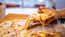 Slice Of Hot Cheesy Italian Pizza Held In Hand And Delivered To Home During Pandemy