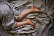 Legs Laying In Bed With Grey Sheets