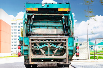Fototapete - A garbage truck picks up garbage in a residential area. Loading mussar in containers into the car. Separate collection and disposal of garbage. Garbage collection vehicle.