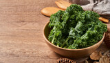 Fototapeta Lawenda - concept of fresh kale leaves salad in a bowl on wooden table background. green kale leaves salad food in the kitchen. spoon, fork                           