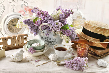 Wall Mural - Table with a cup of coffee and a bouquet of colorful lilac blossoms in shabby chic interior