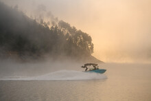 Great View On Boat Quickly Floating On The Water Against The Backdrop Of Silhouette Of Hill In Fog