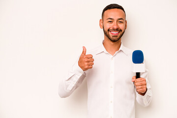 Wall Mural - Young hispanic TV presenter isolated on blue background smiling and raising thumb up