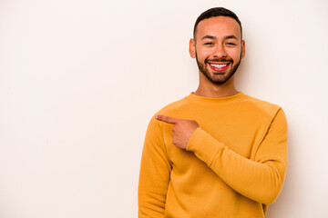 Wall Mural - Young hispanic man isolated on white background smiling and pointing aside, showing something at blank space.