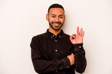 Wall Mural - Young hispanic man isolated on white background winks an eye and holds an okay gesture with hand.