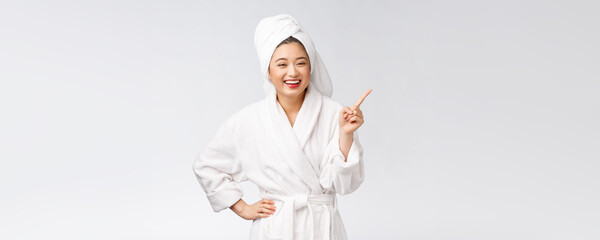 Wall Mural - Beauty portrait of young woman showing and pointing finger to empty copy space, asian beauty in bathrobe.