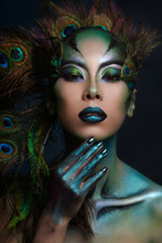 Beautiful Asian Girl With Creative Makeup In The Form Of A Peacock On A Dark Background.