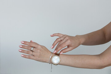 Wall Mural - Female hands with trendy pink maniqure silver jewelry, wristwatch shooted above white background