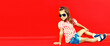 Summer portrait of little girl child wearing sunglasses, checkered shirt on red background in the city