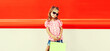 Little girl child with shopping bags in the city on red background