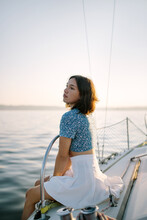 Stylish Female Tourist Resting On Yacht And Admiring Sunset Over Sea