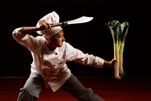 Young Female Mime Artist With Knife And Leeks Performing Martial Arts Pose