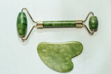 Fototapeta Konie - massage stone jade gouache scraper and facial roller light background.