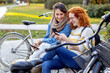 © pucko_ns - Two friends woman sitting on the bench and looking at mobile phone and smile