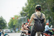 © DragonImages - Young man with backpack wearing helmet when riding bicycle in city, view from back