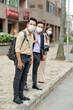 © DragonImages - Group of businesss people in medical masks waiting for bus or taxi to go home after work