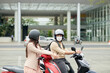 © DragonImages - Business colleagues wearing protective helmets when riding on scooters to office in morning