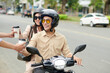 © DragonImages - Smiling businesss couple on scooter ordering coffee in drive through restaurant on way to work