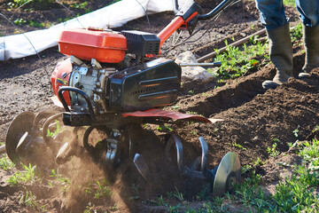 A man plowing the soil with a motocultivator