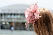 A women in a pink lace hat at a horse race.