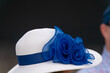a white hat with blue ribbon at a horse race.