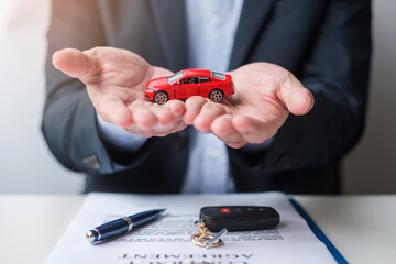 Wall Mural - Businessman hand holding red car toy with vehicle keyless, pen and contract document. buy and sale, insurance, rental and contract agreement concepts