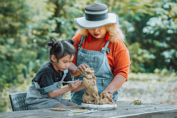 Portrait of little girl and teacher working with pottery clay together, happy kid creating handmade pottery in art class. Vintage filter effect