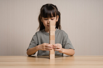 Girls build wooden cubes in layers with wooden blocks cube wooden box. girl playing with wooden block toys. Concept of early child development