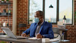© DC Studio - Financial analyst taking notes on business documents browsing internet on laptop, doing paperwork to plan strategy. Businessman with face mask writing statistics report. Tripod shot.