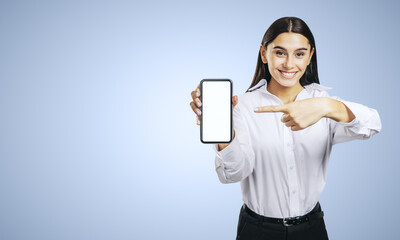 Mobile application concept with smiling businesswoman in white shirt showing modern cellphone with white blank screen on abstract light blue background with place for your logo or text, mockup