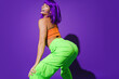 © blackday - Carefree woman wearing colorful sportswear twerking against purple background