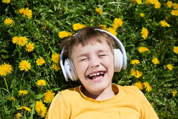 Audio healing. meditation. Slow life. Enjoying the little things. Dreaming of spring. a preteen boy wearing headphones listens to music lying on the grass on a spring day