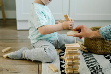 Wall Mural - Happy father and toddler boy child little son playing with wooden blocks in children room at home