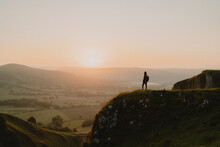 Silhouetted Female Hiker On Hilltop Overlooking Tranquil Landscape At Sunrise, England
