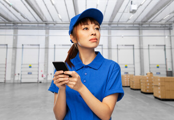 Sticker - logistics, shipping and job concept - delivery woman in blue uniform with smartphone over warehouse background