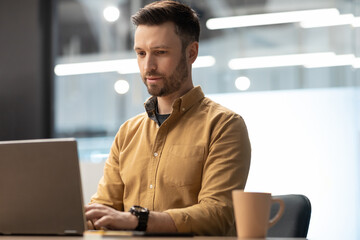 Poster - Male Office Worker Working On Laptop Sitting At Workplace Indoor