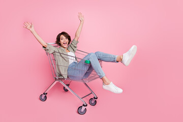 Sticker - Full size portrait of astonished positive lady sit in trolley raise hands have fun isolated on pink color background