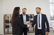 © Studio Romantic - Handsome confident businessman shakes hands with his female colleague during meeting in office. Two business men meet new business partner and welcome her as new team member. Business people concept.
