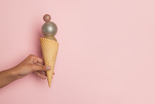 Christmas Ice Cream. Waffle Cone With Xmas Balls Decoration In Female Hand On Pink Banner Background