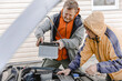 © Enigma - Auto mechanics, Caucasian White mans, working in a car repair shop. Installing the new battery under the hood.