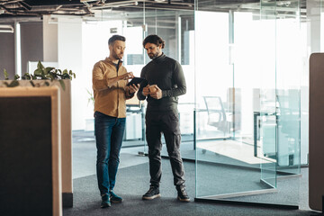 Canvas Print - Experienced mentor explaining to serious young coworker business project strategy at modern office, empty space