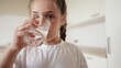 © ibragimova - child girl drinking water from a glass cup. the problem of lack of clean drinking water in the world. little girl in the kitchen drinks drinking water lifestyle from a transparent glass cup