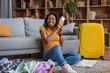 © Prostock-studio - Ready for vacation. Overjoyed black woman holding passport and tickets, sitting near suitcases at home