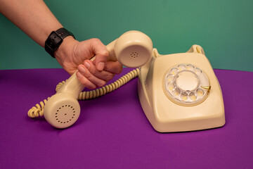 Woman's hand picking up an old phone.