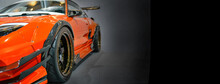 Front Headlights Of Orange Modify Car On Black Background, Copy Space