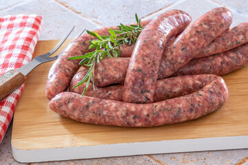 Wall Mural - sausages with raw herbs on a wooden board on a table