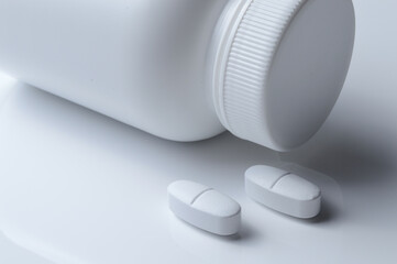 Wall Mural - white plastic medicine jar and two white pills. light background