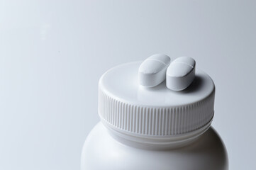 Wall Mural - white plastic medicine jar and two white pills. light background