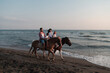 © .shock - The family spends time with their children while riding horses together on a sandy beach. Selective focus